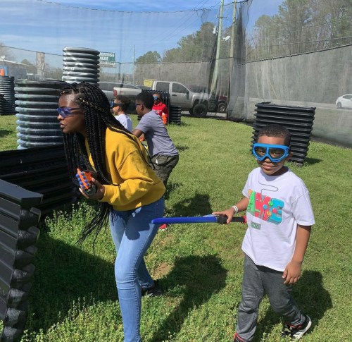 A group of children playing in a paintball arena, wearing protective gear and having fun outdoors.