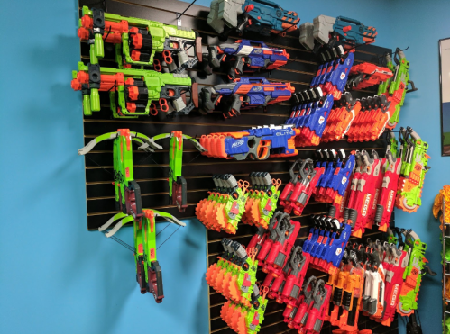 A colorful display of various toy blasters and crossbows mounted on a wall.