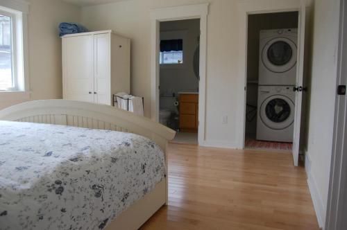 A bright bedroom with a floral bedspread, a closet, and a laundry area visible through an open door.