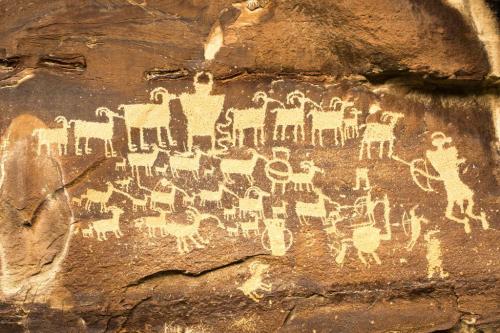 Petroglyphs depicting various animals and human figures carved into a rocky surface.