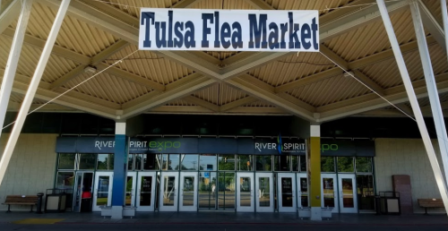 Entrance of the Tulsa Flea Market, featuring a large sign and modern building design.