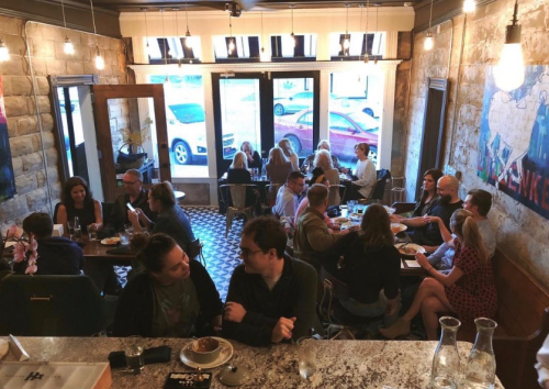 A bustling restaurant scene with diners at tables, enjoying meals and drinks in a cozy, well-lit atmosphere.