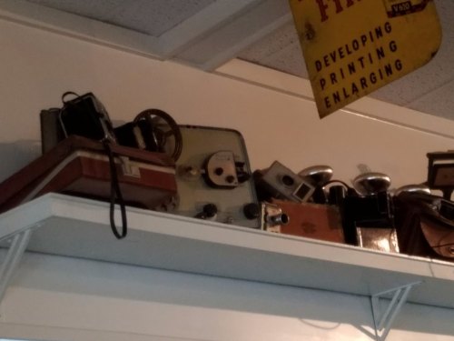 A collection of vintage cameras and photography equipment displayed on a shelf.