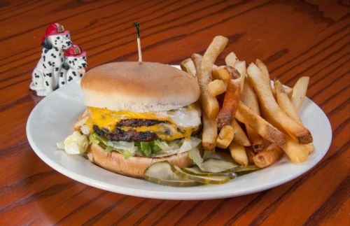 A cheeseburger with lettuce and pickles, served with a side of golden fries on a white plate.