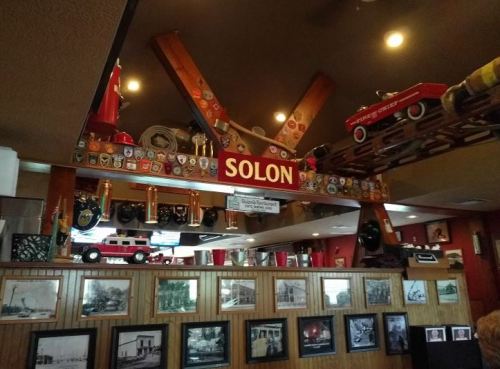 Interior of a restaurant featuring a "Solon" sign, vintage memorabilia, and black-and-white historical photos on the walls.