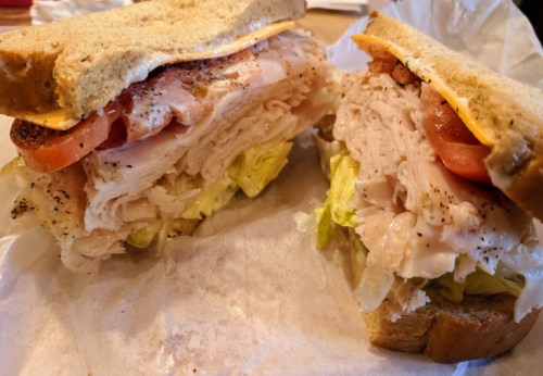 A hearty sandwich with layers of turkey, lettuce, tomato, and cheese between two slices of whole grain bread.