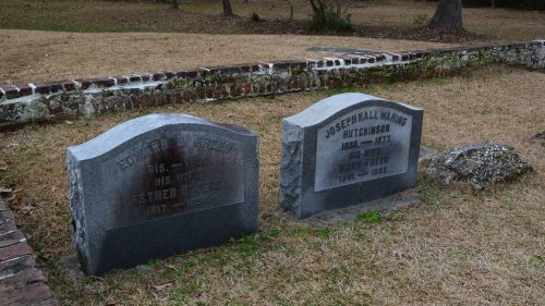 Two gravestones in a grassy area, one for Edward P. Reed and the other for Joseph Hall Waring Hutchinson, with dates.