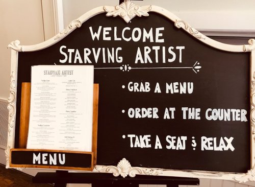 A chalkboard sign welcoming guests to "Starving Artist" with instructions to grab a menu, order at the counter, and relax.