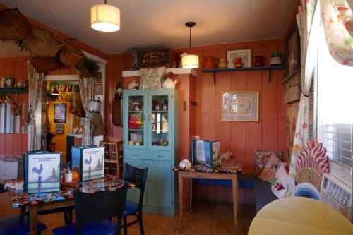 Cozy interior of a colorful café with wooden tables, a blue cabinet, and decorative wall art.
