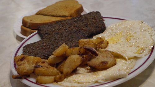 A plate of breakfast featuring two fried eggs, hash browns, and two slices of toast.