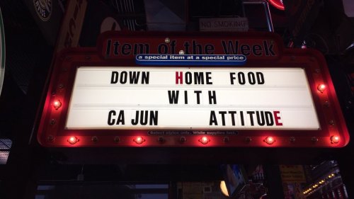 Sign reading "Item of the Week: Down Home Food with Cajun Attitude" in a vibrant, illuminated display.