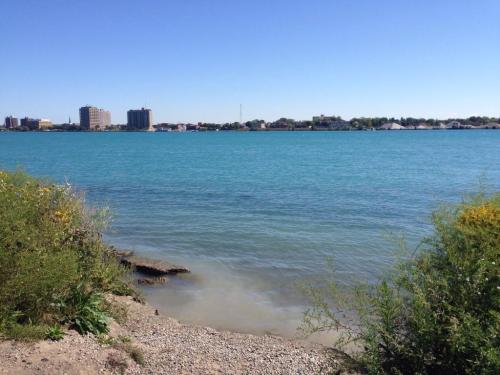 A serene view of a turquoise river with a city skyline in the background under a clear blue sky.
