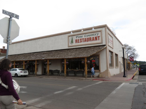 A street view of Pine Country Restaurant, featuring a rustic exterior and outdoor seating, with a pedestrian nearby.