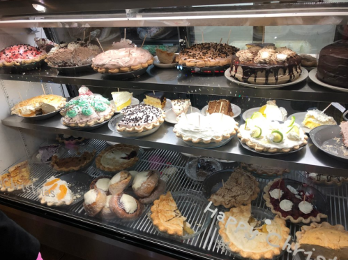 A display case filled with various cakes and pies, including cream pies, fruit tarts, and chocolate desserts.