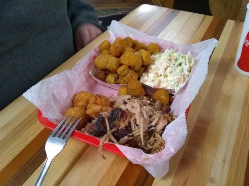 A tray with pulled pork, coleslaw, and fried okra, served on a wooden table.