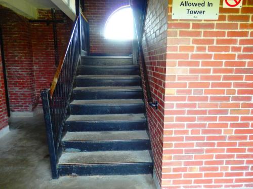 Staircase leading up with a brick wall on one side and a sign indicating tower access rules.