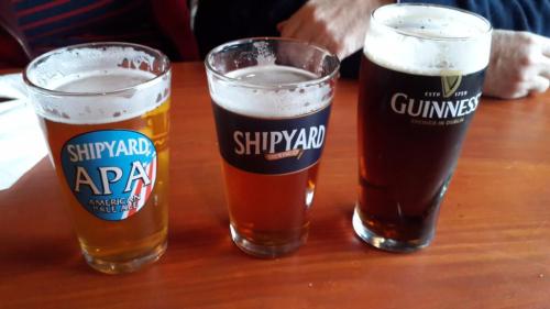 Three glasses of beer on a wooden table: a light APA, a medium amber, and a dark Guinness.