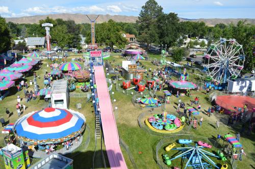 A vibrant carnival scene with rides, games, and colorful tents, bustling with visitors enjoying the festivities.