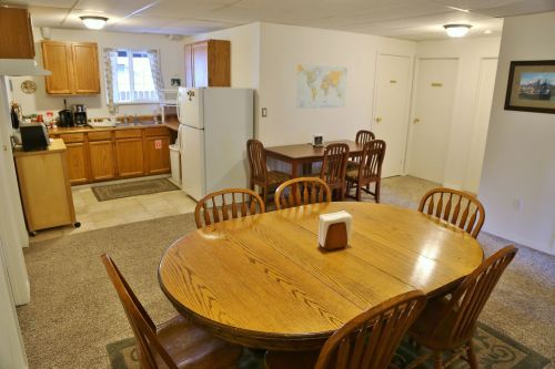 A cozy kitchen and dining area with a wooden table, chairs, and a well-equipped kitchen in a bright, inviting space.