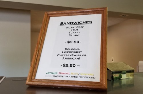 Menu sign displaying sandwich options and prices: Roast Beef, Ham, Turkey, Salami, Bologna, Liverwurst, and Cheese.