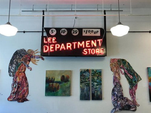 Neon sign reading "Lee Department Store" with colorful artwork on the walls, including two large figures.