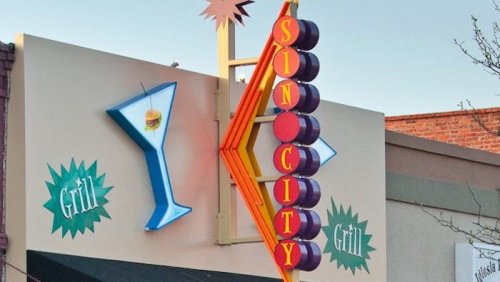 Colorful sign for "Sin City Grill" featuring a cocktail glass and burger illustration.