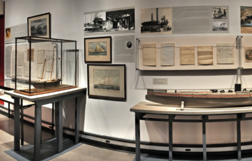 A museum display featuring ship models, historical photographs, and documents related to maritime history.