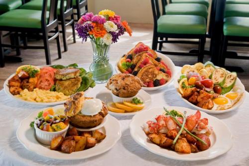 A table set with various colorful dishes, including seafood, fruits, pancakes, and a flower vase centerpiece.