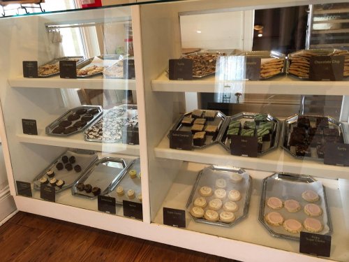 Display case filled with various baked goods, including cookies, brownies, and bars, labeled with names.