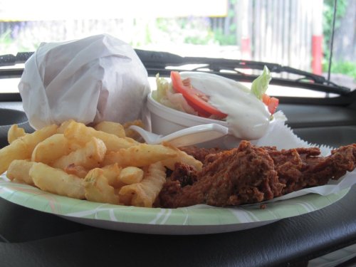 A plate of fried chicken, crinkle-cut fries, a wrapped sandwich, and a side salad with dressing.