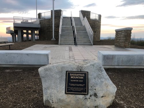 View of Sassafras Mountain with stone steps leading up, a plaque on a rock, and a scenic sky in the background.