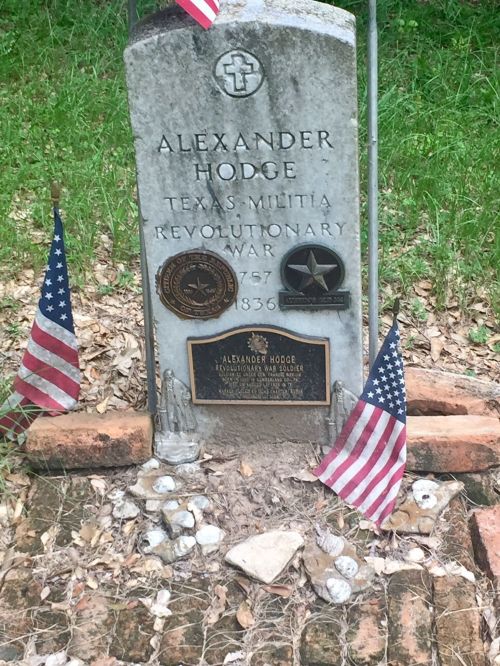 Gravestone of Alexander Hodge, Texas Militia, Revolutionary War, with flags and decorative stones around it.
