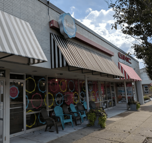A storefront with colorful signage and awnings, featuring a shop named "treat" and a GNC next door.