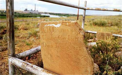 A weathered gravestone with the inscription "A.H. Unthank, W. & Co. Ind, Died Jul. 2, 1859," set in a grassy landscape.