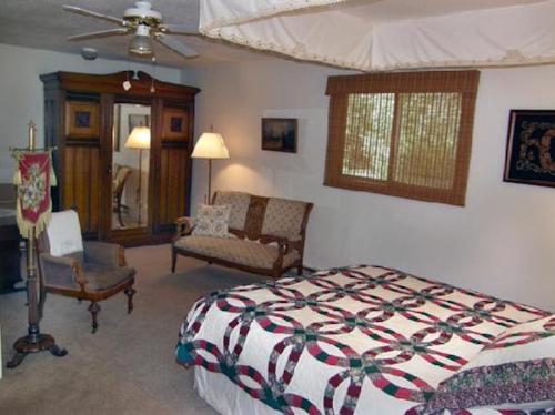 Cozy bedroom featuring a quilted bed, vintage furniture, a mirror, and natural light from a window.