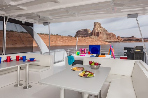 A spacious boat interior with tables set for snacks, colorful cups, and a scenic view of rock formations outside.