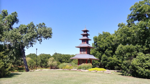 A tall, multi-tiered pagoda surrounded by greenery under a clear blue sky.