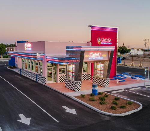 A colorful fast-food restaurant with neon lights and a retro design, set against a twilight sky.