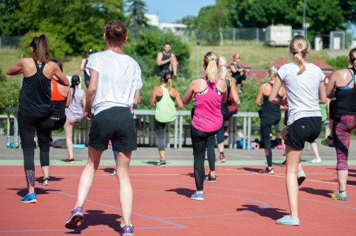 A group of women participating in an outdoor fitness class on a sunny day, focused on their workout.