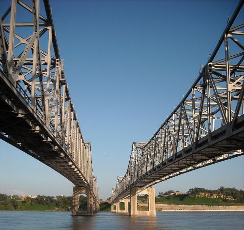 A view of two steel bridges spanning a river under a clear blue sky.