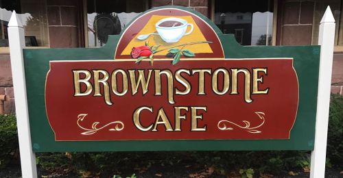 Sign for Brownstone Cafe featuring a coffee cup and a rose, set against a red and green background.