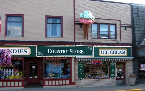 A charming country store with an ice cream shop, featuring a large ice cream cone sign and colorful storefront displays.