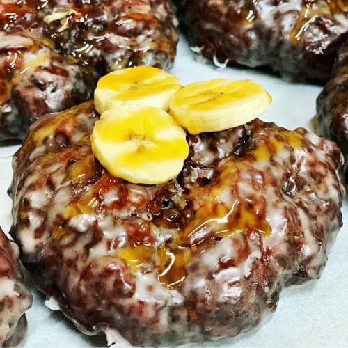 Close-up of a glazed pastry topped with banana slices and drizzled with syrup.