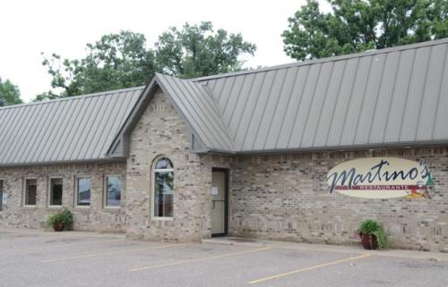 Exterior of Martino's Restaurant, featuring a brick facade, large windows, and a sloped metal roof.