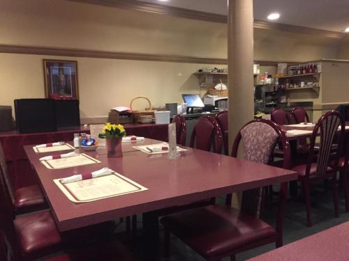 A cozy restaurant interior with maroon tables and chairs, featuring a small kitchen area in the background.