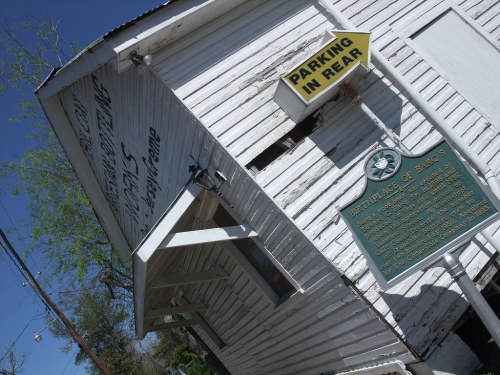 Historic building with a tilted sign reading "Parking in Rear" and a plaque stating "Birthplace of Barqs."