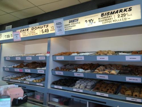 A display case filled with various donuts and pastries, with price tags for each item visible above.