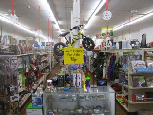 A colorful store interior with holiday decorations, featuring a bike hanging from the ceiling and a sign for local honey.