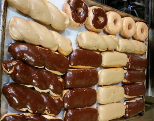 A tray of assorted donuts, including chocolate-covered, cream-filled, and plain varieties.