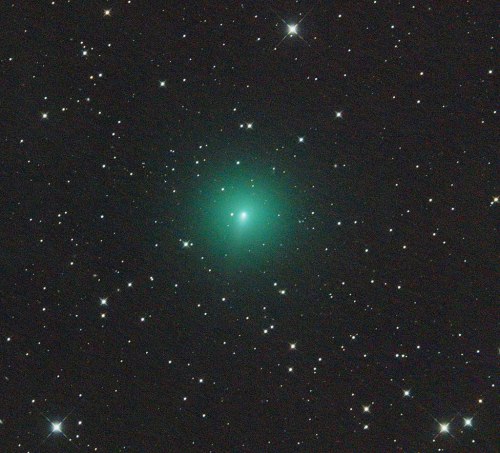 A bright green comet surrounded by a field of stars in a dark night sky.